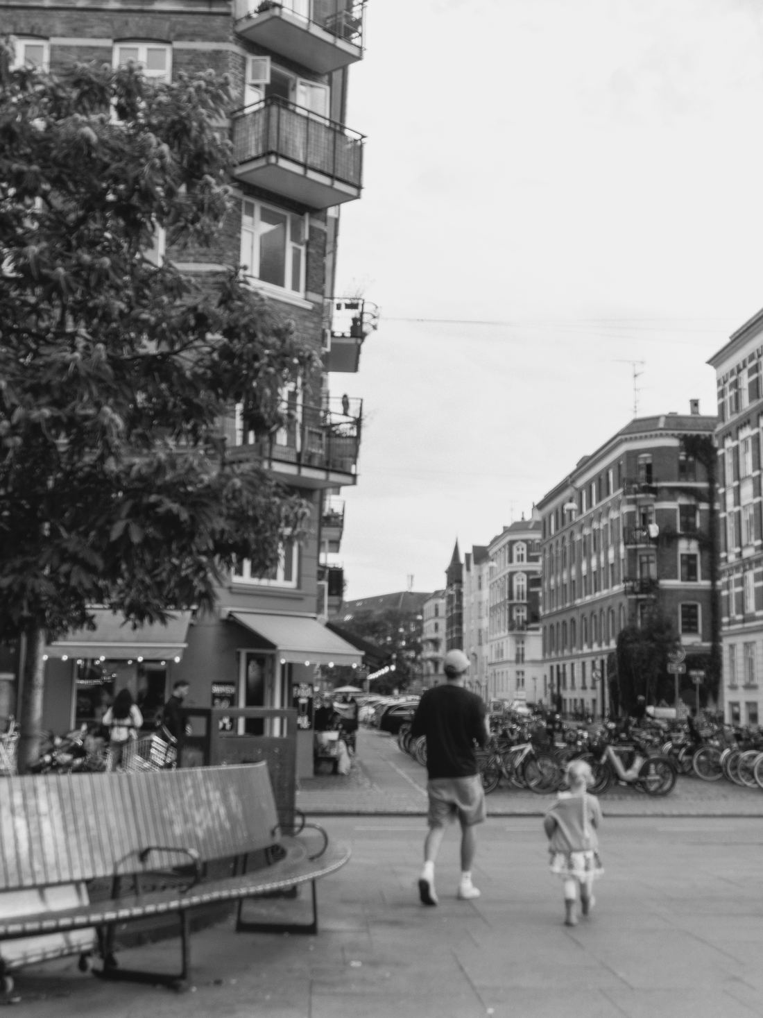 An adult and a small child walking away across a Copenhagen square