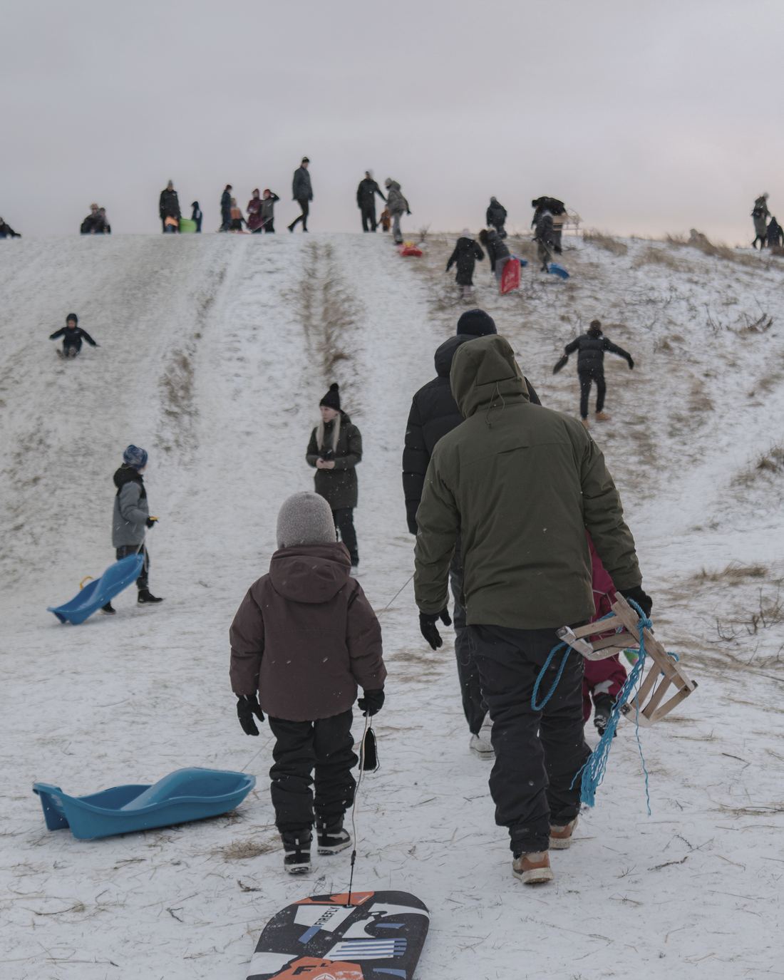 A family walking up a snowy hill, seen from behind