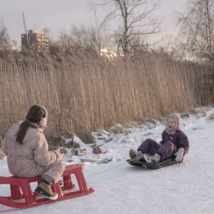 Two children on sledges in low winter light