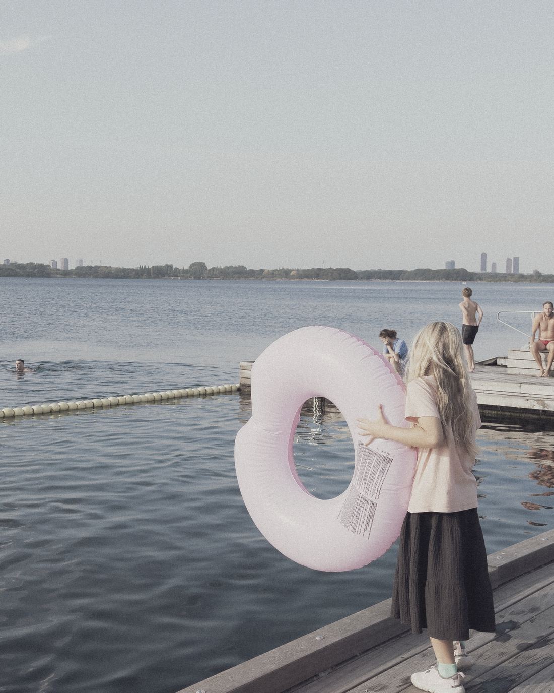 A girl carrying a swim ring at the harbour bath, seen from behind